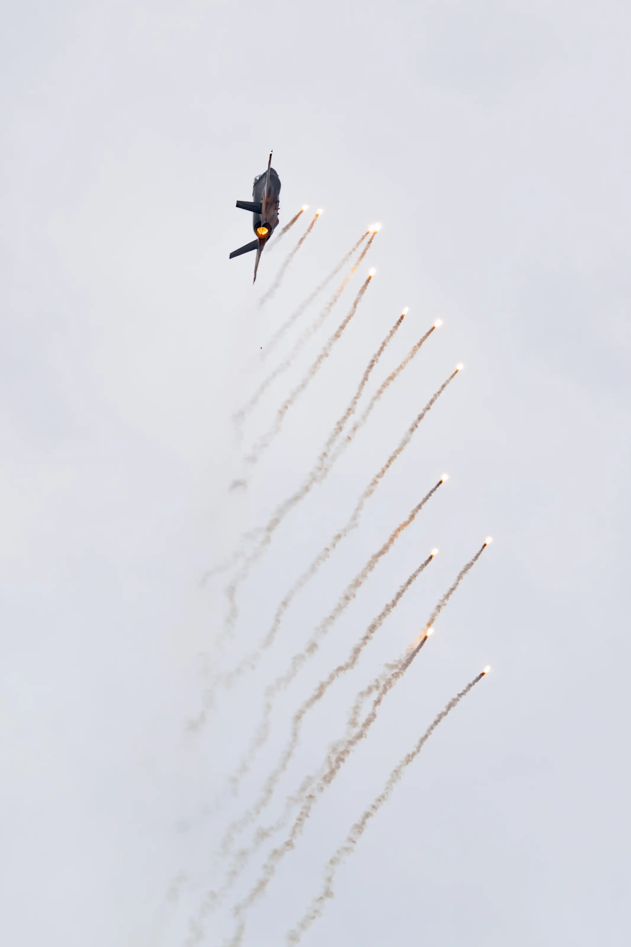 A jet climbing with flare trails cascading behind