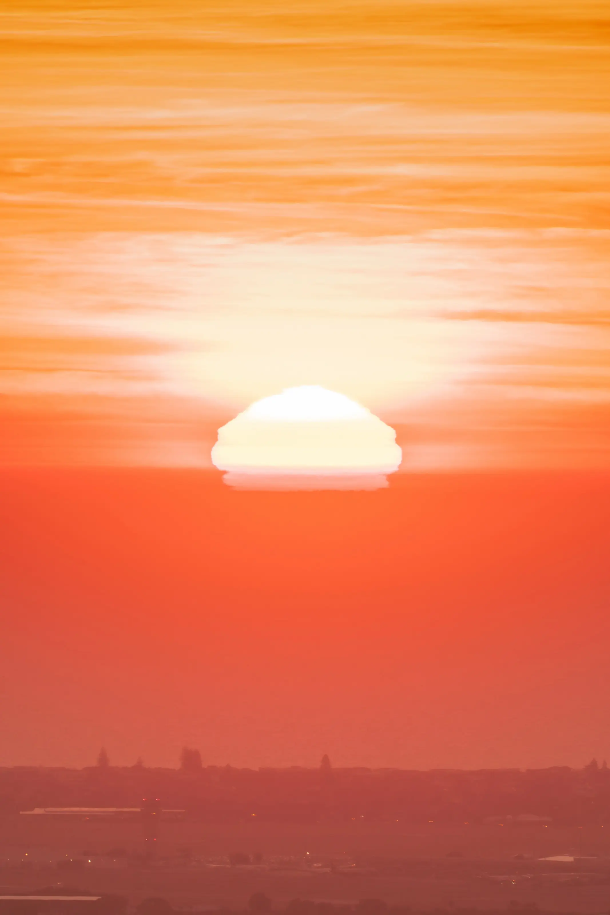 The sun sinking into a sea of haze, sky burning orange
