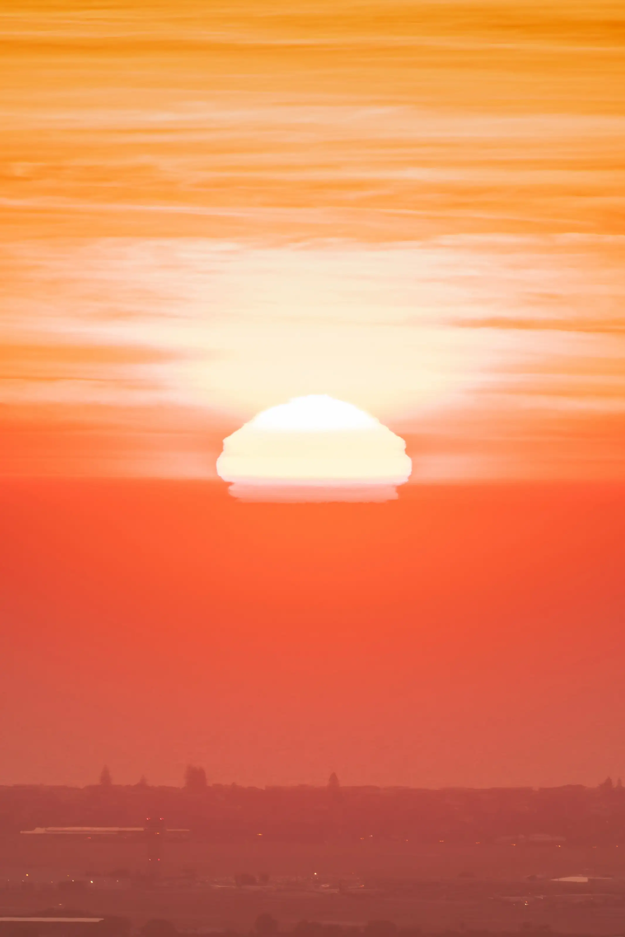 The sun sinking into a sea of haze, sky burning orange