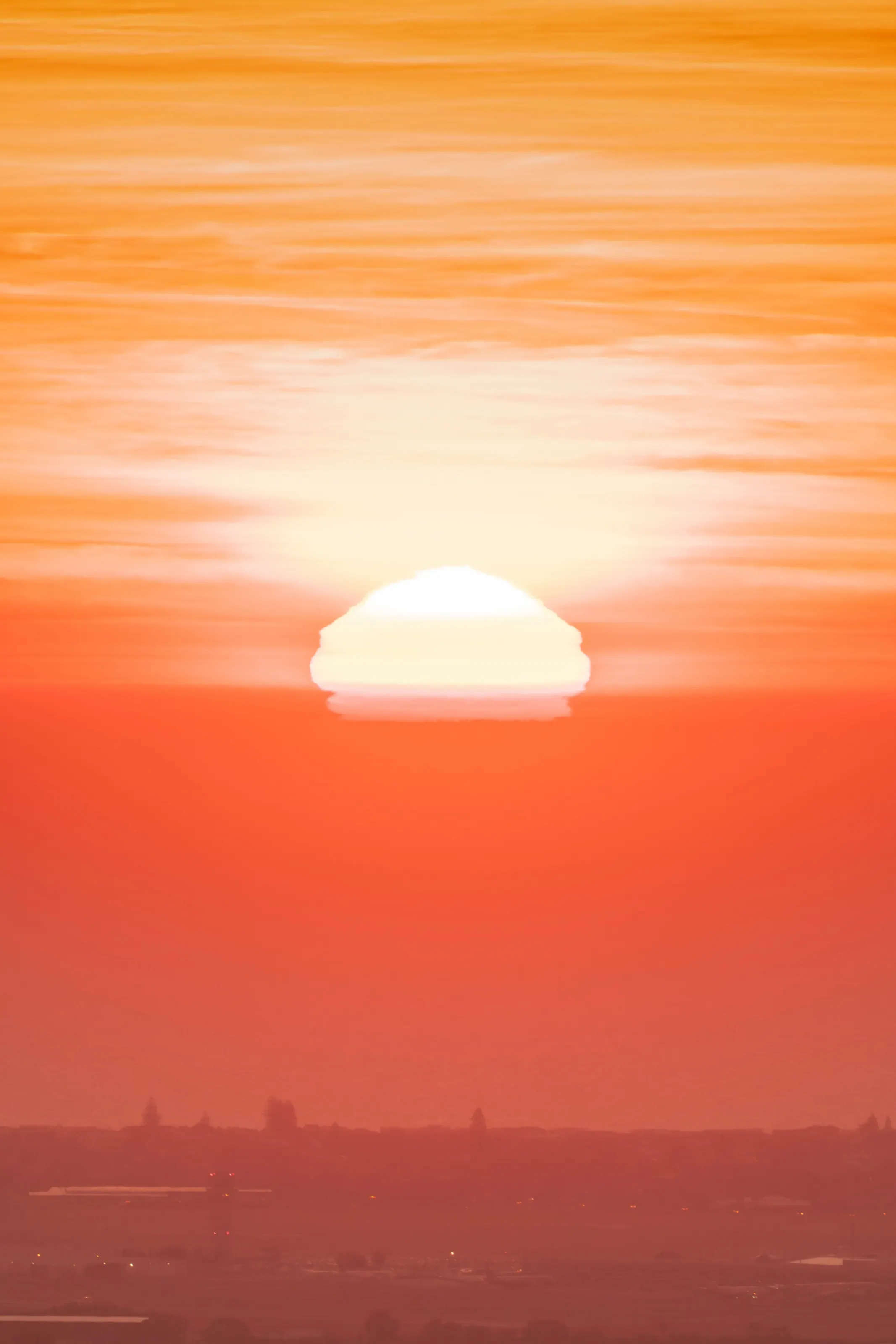 The sun sinking into a sea of haze, sky burning orange