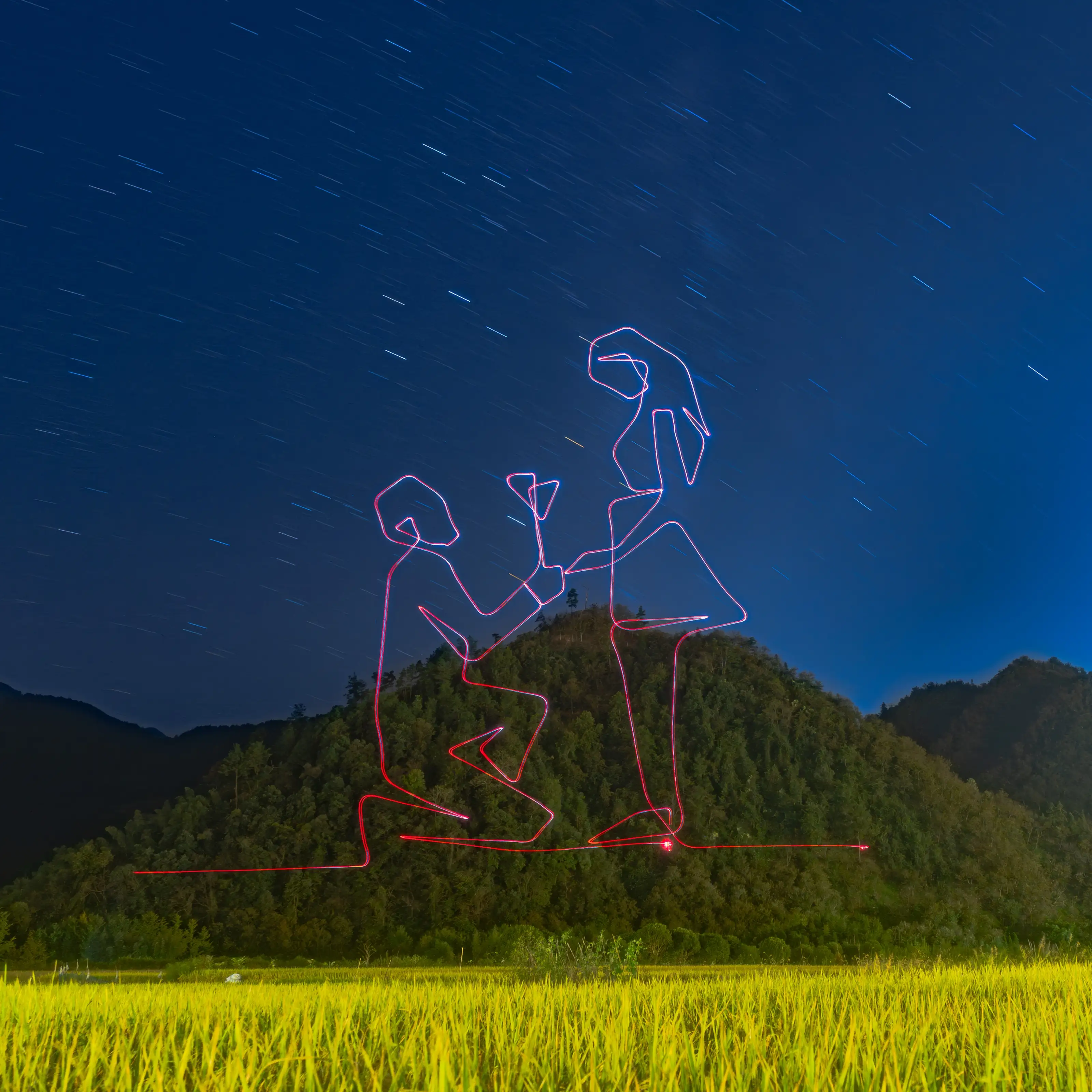 Light painting of a couple beneath star trails